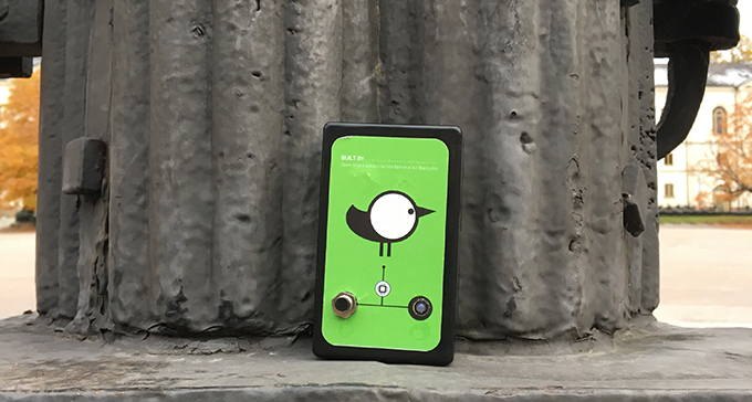 Grön fyrkantig syntfågel lutad mot pelare.